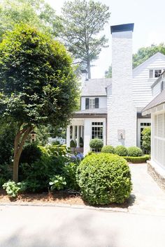 a white house surrounded by trees and bushes