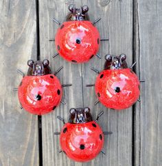 four red glass ladybugs sitting on top of a wooden table