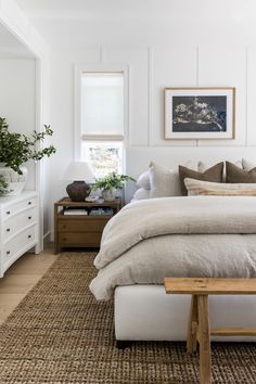 a bedroom with a bed, dresser and window in the corner that has plants on it