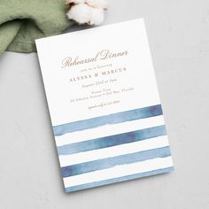 a blue and white striped wedding card on top of a green napkin next to a cotton ball