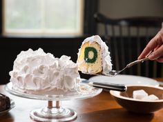 a person is holding a piece of cake with the letter o on it, while another slice has been taken out