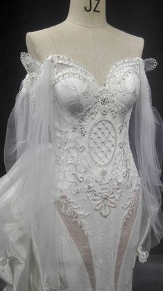 a white wedding gown on display in front of a mannequin