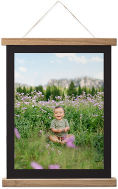 a little boy sitting in the middle of a field with purple flowers on his chest