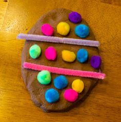 a chocolate cookie decorated with colored pom - poms on top of a wooden table