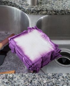 a purple and white dish towel sitting on top of a kitchen sink