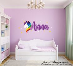 a child's bedroom decorated in pink and purple with an unicorn wall decal