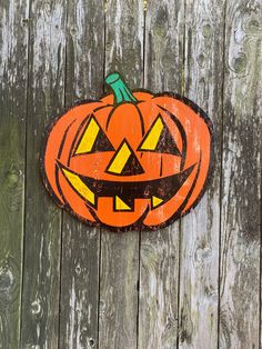 a carved pumpkin sitting on top of a wooden fence