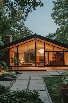 a glass house in the middle of a park at night with trees and grass around it