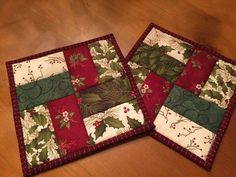 two quilted placemats sitting on top of a wooden table next to each other