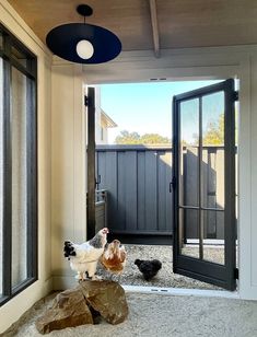 two chickens are standing in front of an open door