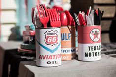 two cans with forks and spoons in them sitting on a table next to other utensils