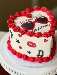 a red and white birthday cake decorated with music notes, heart - shaped sunglasses and lips