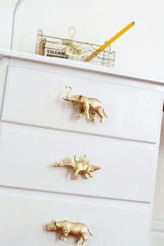 three gold rhinoceros on white drawers in a bedroom