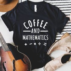 a black shirt that says coffee and mathematicas next to a guitar, hat, and other items