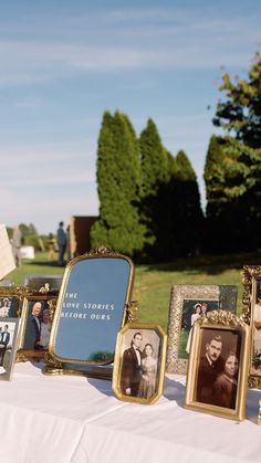 a table topped with pictures and framed photos next to a white cloth covered tablecloth