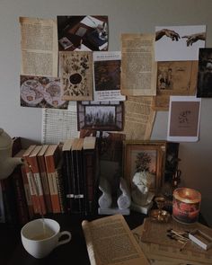 a table topped with lots of books next to a cup and candle on top of it