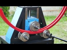 a machine that has some red hoses in it's mouth and is on the ground