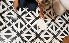 a woman is sitting on the floor and looking down at something in her hand while holding a piece of paper