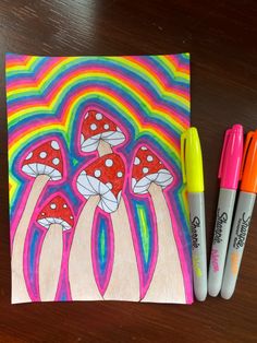 two markers are next to a drawing of three mushrooms on a rainbow colored background and one is orange