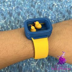 a person wearing a yellow and blue watch with rubber ducks on it's wrist