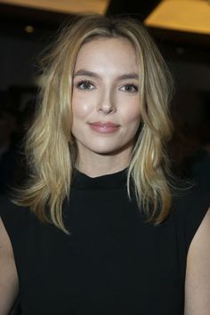 a woman with blonde hair wearing a black dress and posing for the camera at an event