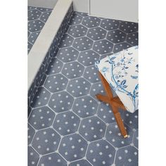 a blue and white tiled floor with a wooden stool in the middle on top of it