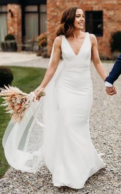 a bride and groom holding hands in front of a brick building