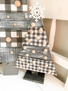 a wooden christmas tree sitting on top of a white table next to a black and white checkered wall