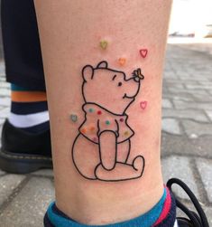 a small tattoo on the leg of a person with a bear and hearts around it