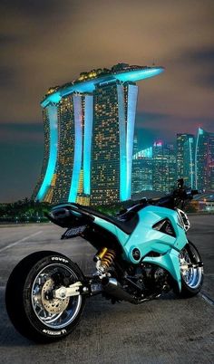 a blue motorcycle parked in front of a tall building with lights on it's side