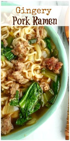 a bowl of soup with meat, noodles and greens in it on a white table