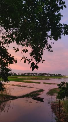 the sun is setting over some water and trees