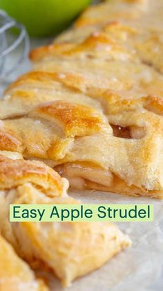 an apple pie sitting on top of a piece of wax paper next to some apples