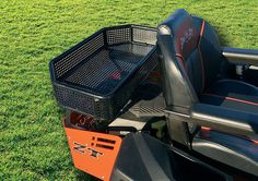 an orange and black cart sitting on top of a lush green field