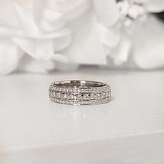 a wedding ring sitting on top of a white table next to a bouquet of flowers