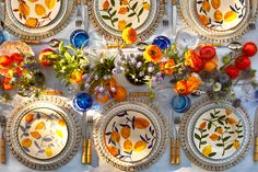 the table is set with colorful plates and flowers