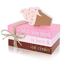 a pink box filled with donuts on top of two other boxes that say, all you need is love and ice cream