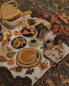 an autumn picnic with pumpkins, cookies and other food on a blanket in the grass