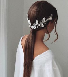 a woman with long hair wearing a white dress and a headpiece that has leaves on it