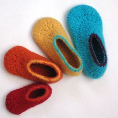 three crocheted slippers laying next to each other on top of a white surface