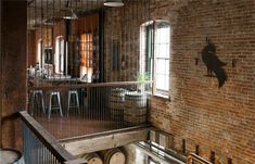 the inside of a brick building with several barrels on the floor and an iron railing