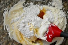 a dessert with powdered sugar on top in a glass pie dish next to a red spatula