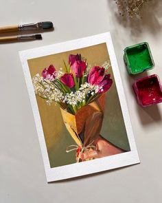 a bouquet of flowers sitting on top of a table next to some colored inks