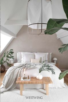 a bed with white linens and pillows in a bedroom next to a wooden coffee table