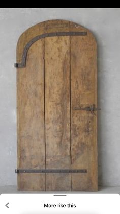 an old wooden door with iron bars on the bottom and side, against a white wall