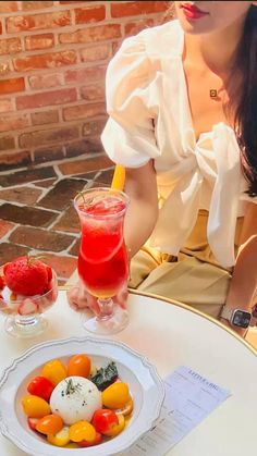 a woman sitting at a table with a plate of fruit