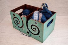 a wooden box with yarn and knitting needles in it