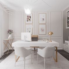 a white table with two chairs and pictures on the wall behind it in a room