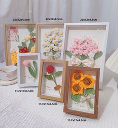 four framed pictures with flowers in them on a table next to a cup and saucer