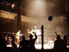 some people are playing with a ball in the middle of a boxing ring at night